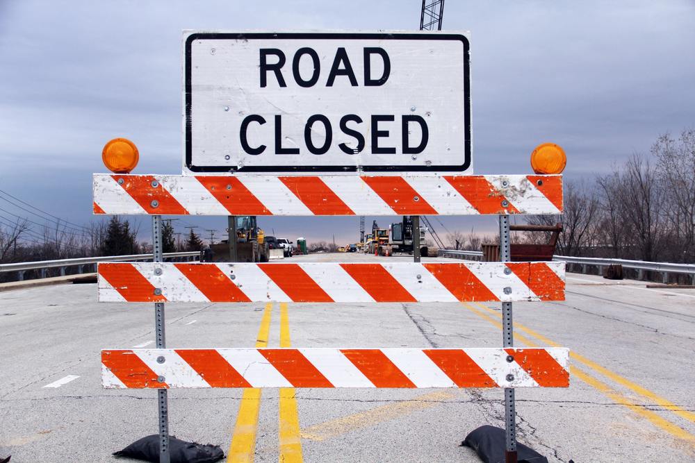 picture of a road with a road closed sign and barricade