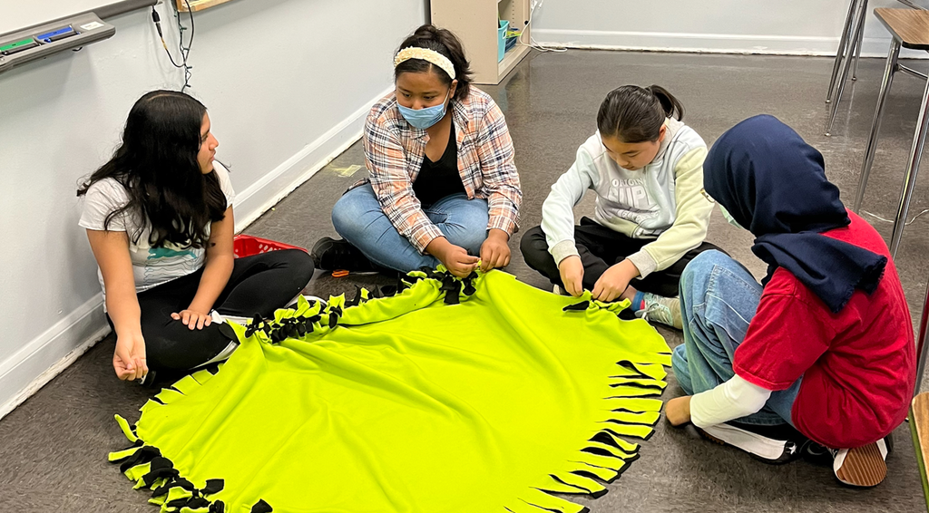 Making blankets for homeless shelter donation