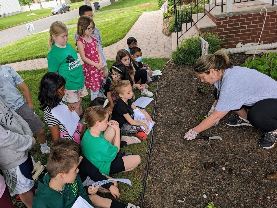 Teacher showing students how to plant flowers